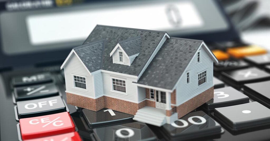 Das Modell eines Hauses steht auf einem Taschenrechner | Immobilie geerbt